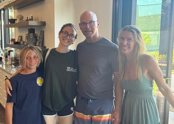 Eric standing indoors with a boy and two women